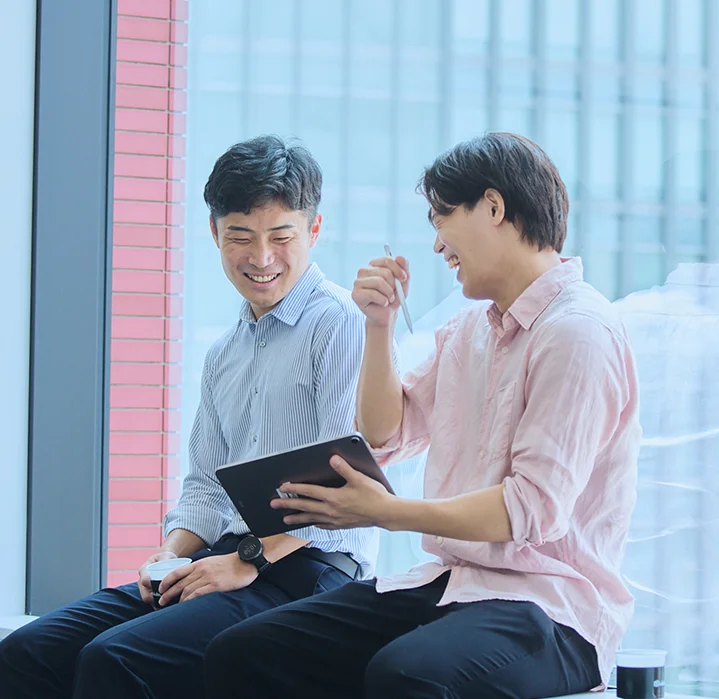 タブレットを使い、先輩社員が後輩にノウハウを共有している様子。