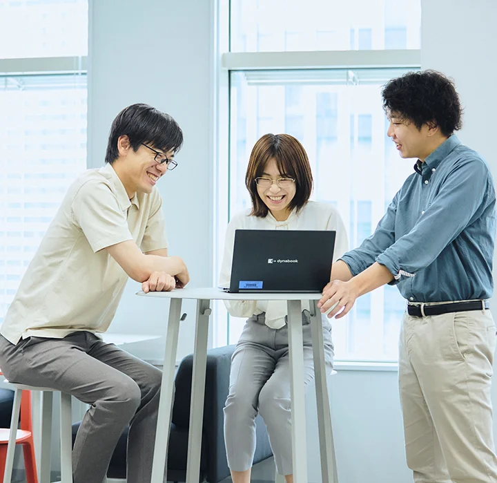 ノートパソコンを囲んでディスカッションする社員たち。気軽にアイデアを出し合える社風。
